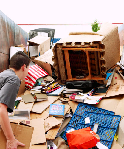 Entrümpelungsservice. Eine Person belädt einen Container mit unterschiedlichen Materialien.