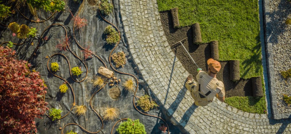 Ein Galabauer arbeitet mit Harke in einem gepflegten Garten.