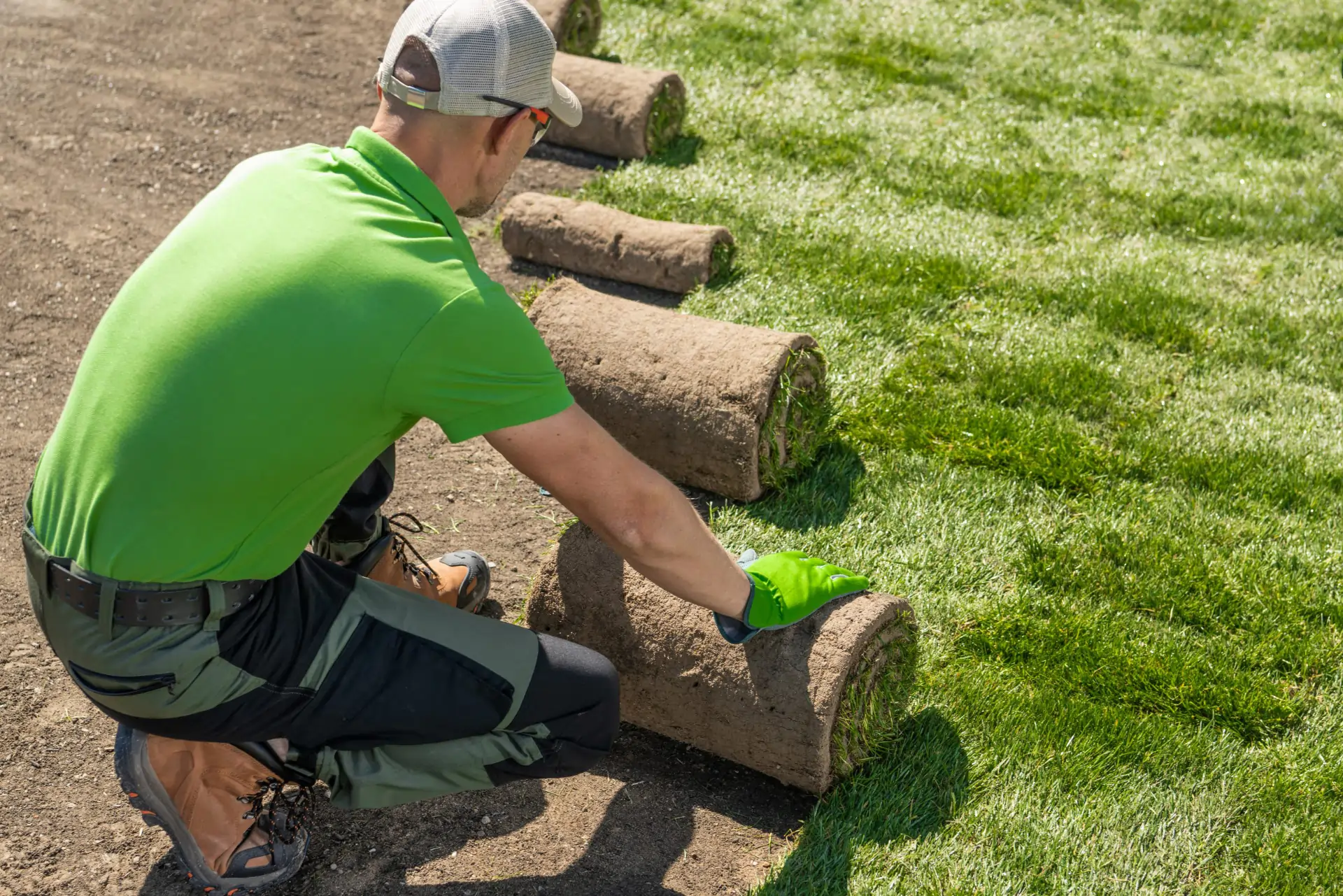 Rollrasen verlegen lassen – Handwerker verlegt frischen Rollrasen auf vorbereitetem Gartenboden